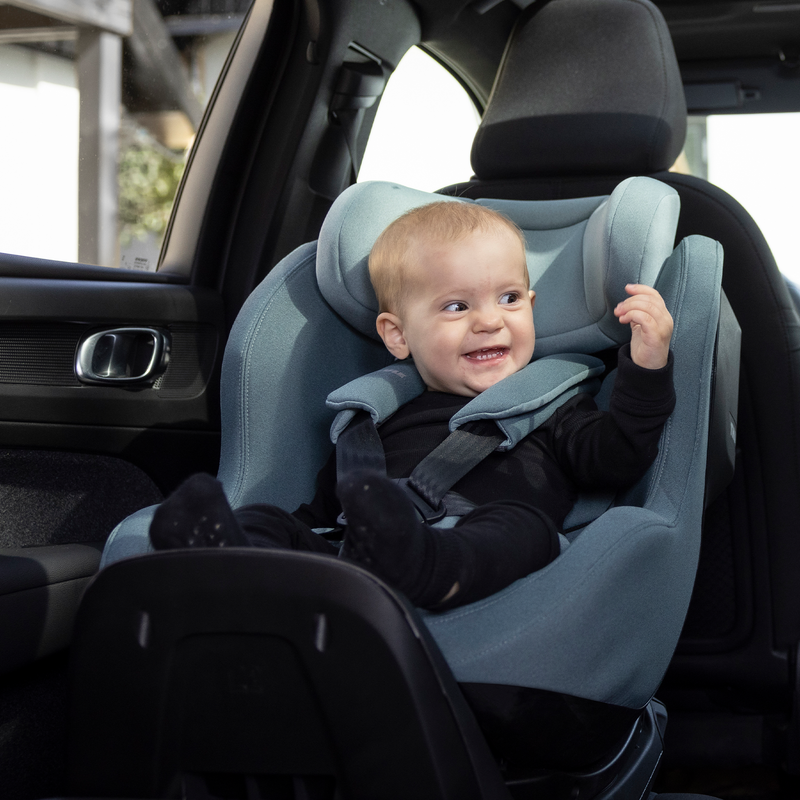 A toddler is sitting in a blue Thule Elm toddler car seat.