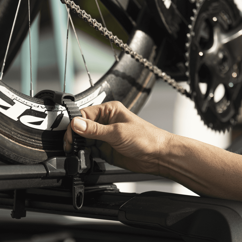 A close-up of someone loading their bikes into the Thule FastRide roof bike rack.