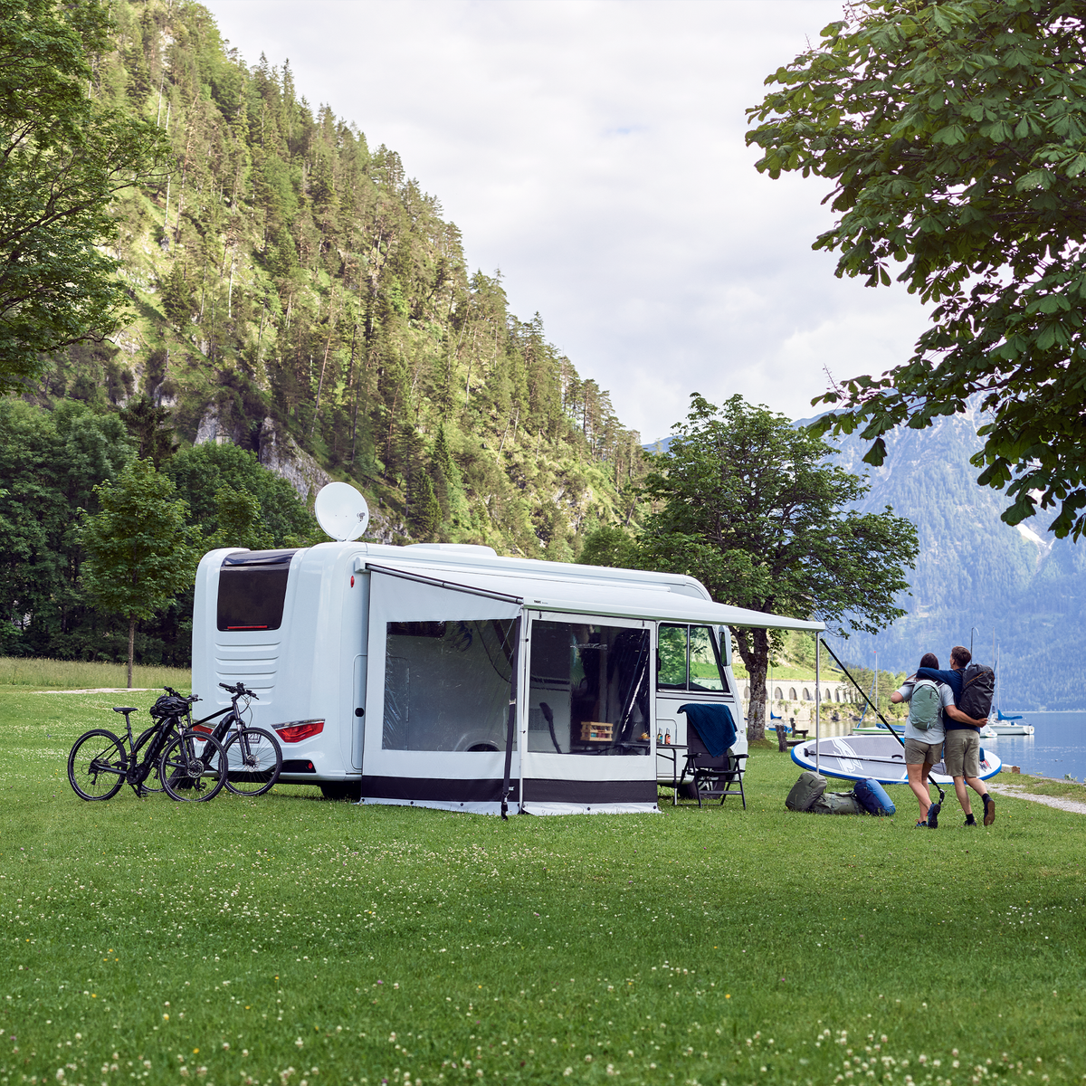 A motorhome parked next to a lake with a Thule Rain Blocker Side awning side wall.