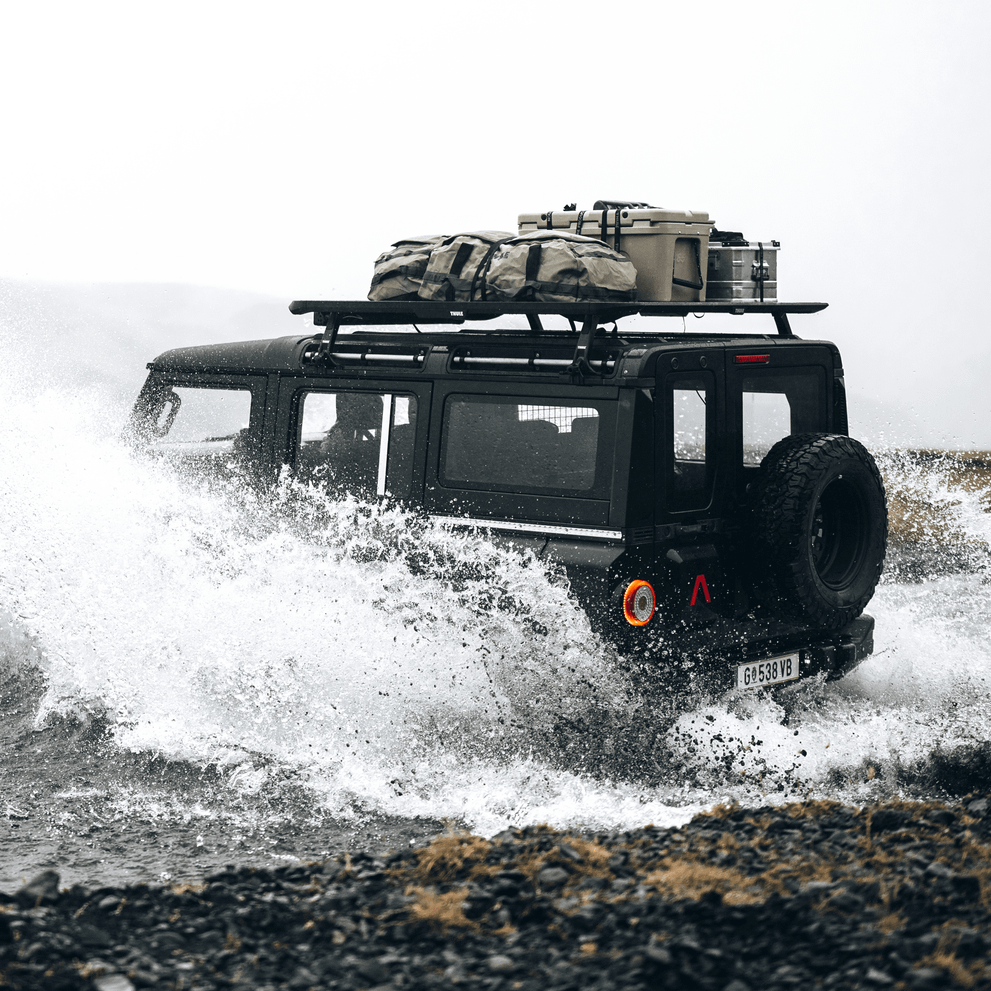 A vehicle drives through a large puddle with a Thule Caprck roof platform.