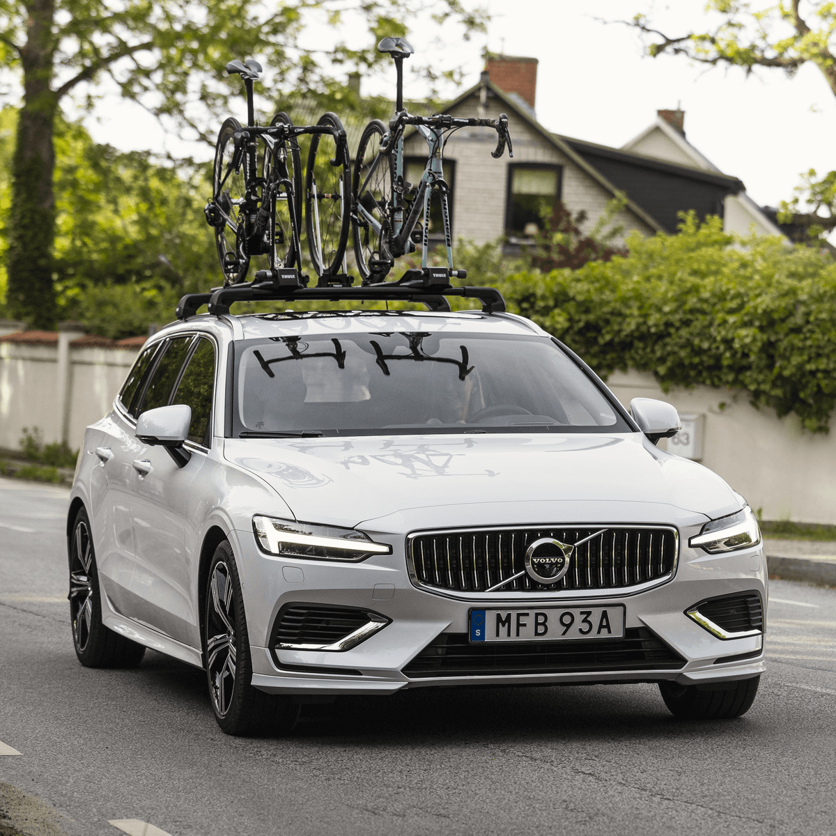A car with several bikes mounted on the roof is approaching.