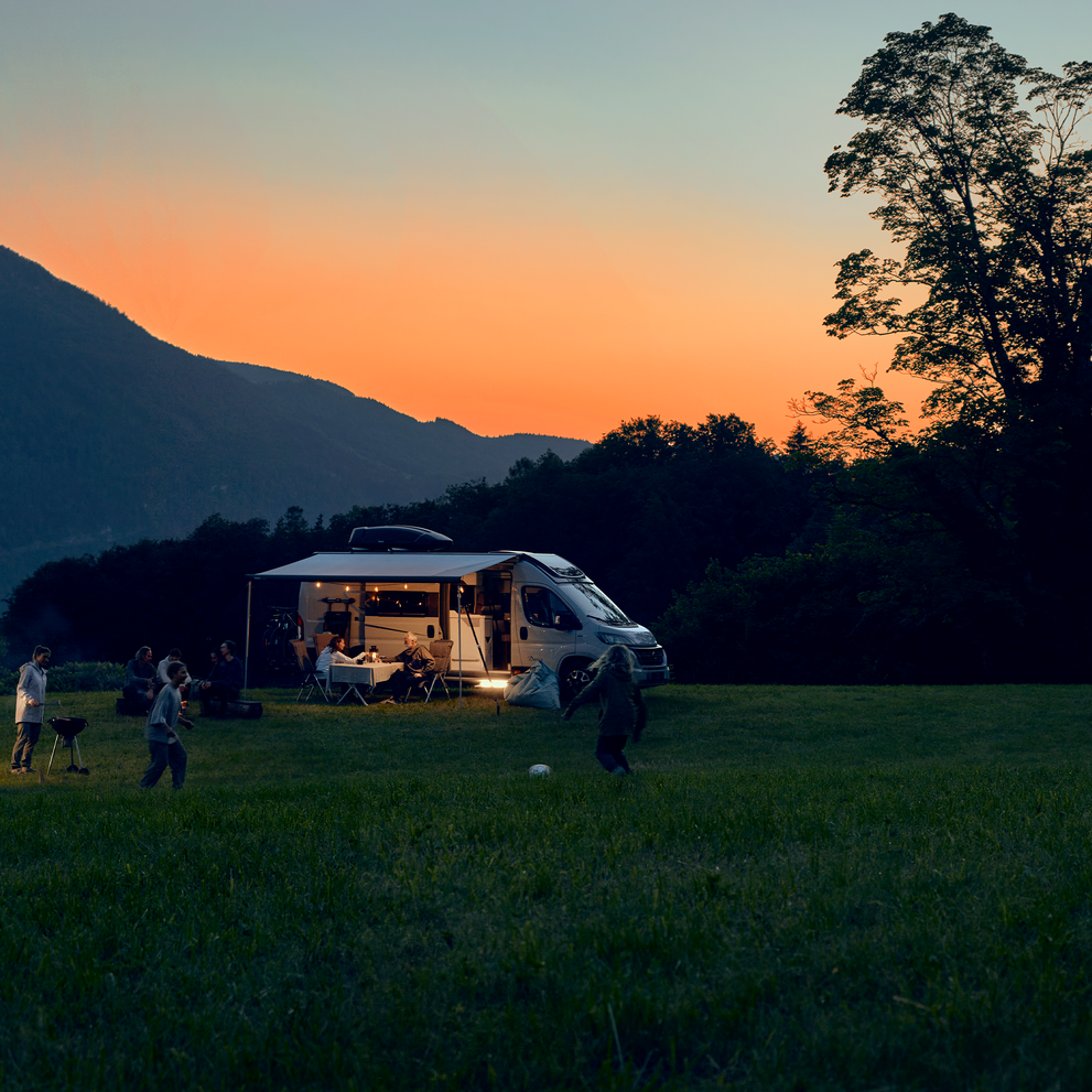 A caravan at sunset has a caravan step with a Thule LED kit for Slide-Out Step Ducato.