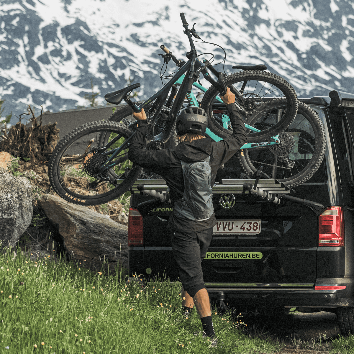 A van is parked near the snowy peaks with a Thule WanderWay 2bike Platform trunk bike rack.