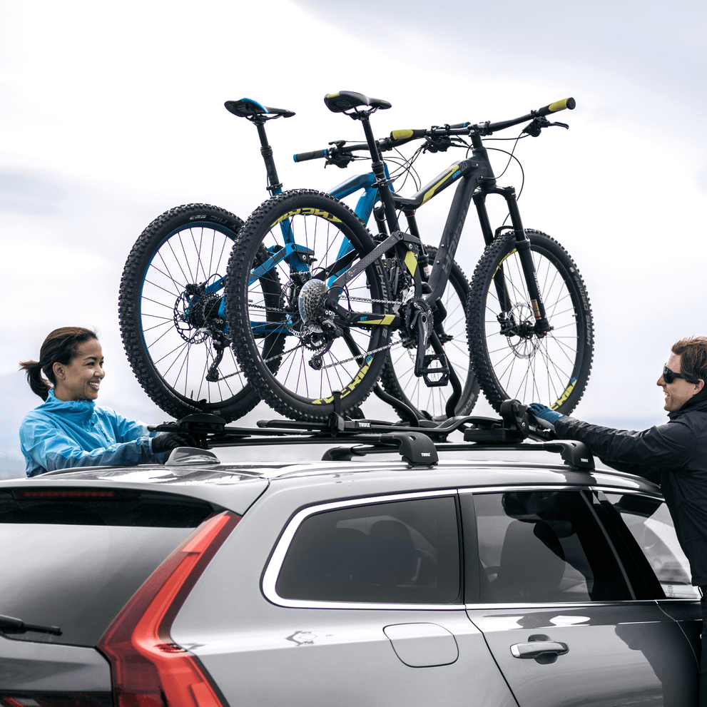 A couple is mounting bikes on their car with a Thule ProRide XT.