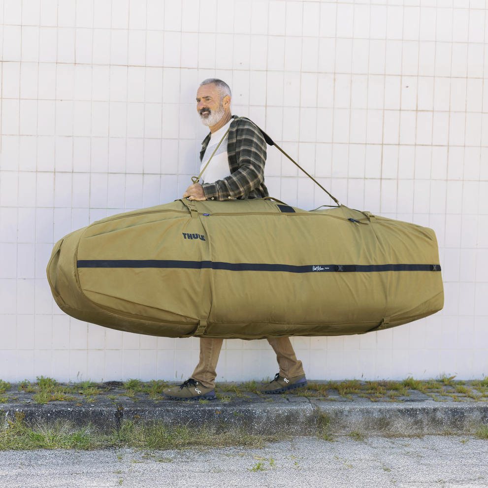A man carrying the Thule Aion surfboard bag with a strap over his shoulder