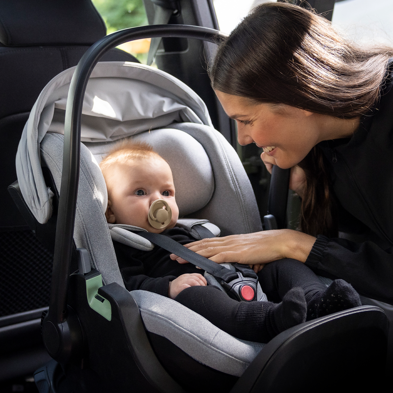 Una madre guarda il suo bambino, seduto in un seggiolino per auto.