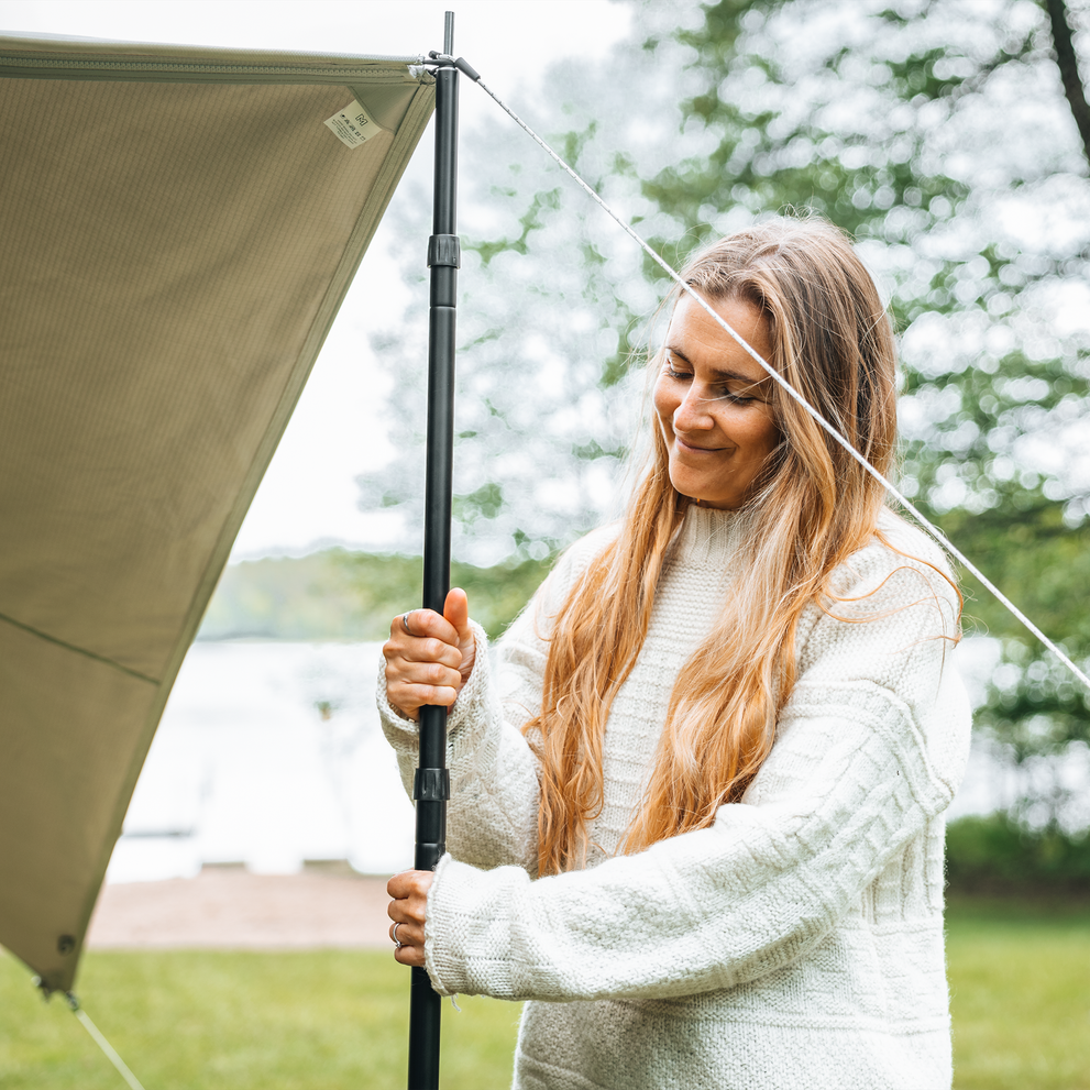 A woman in a white sweater using a pole to set up panels.