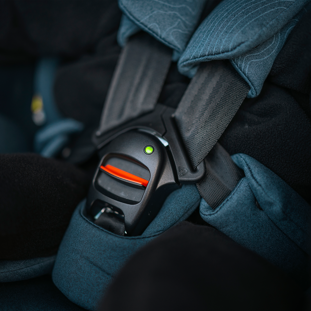 Close-up of the eBuckle on a Thule Elm Connect toddler seat with a green indicator confirming the harness is tightened correctly.