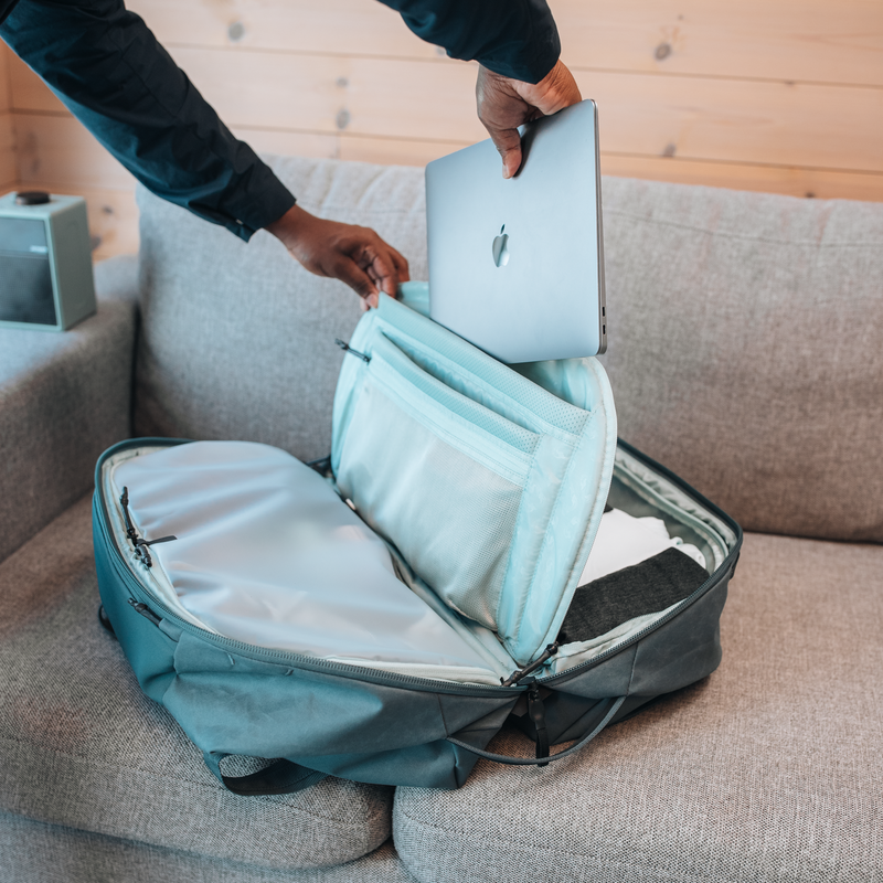 A close-up of someone putting a laptop into the blue Thule Aion laptop duffel.