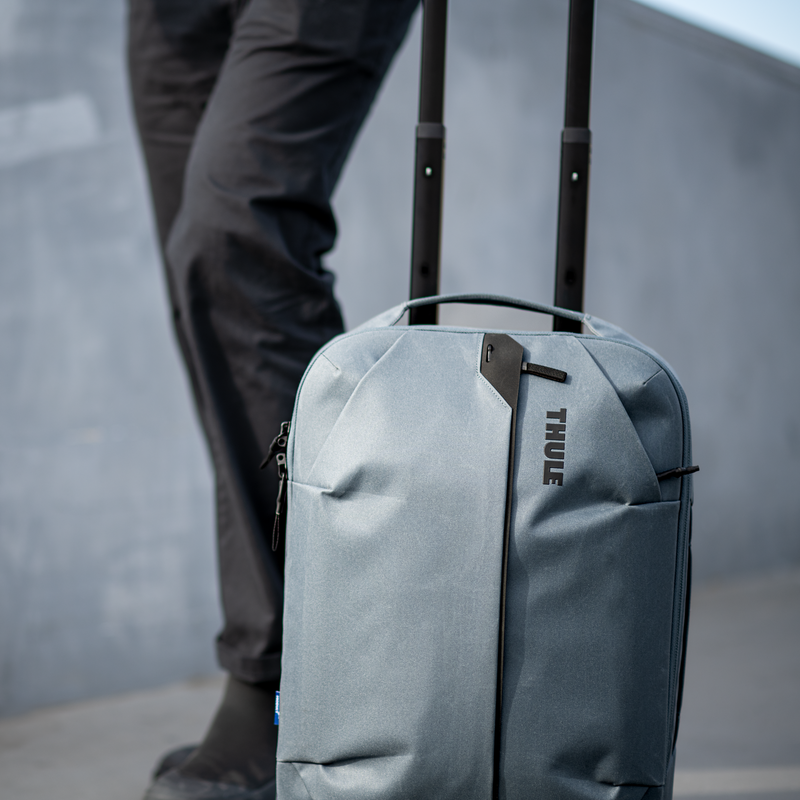 A close-up of someone rolling the blue Thule Aion carry-on suitcase.