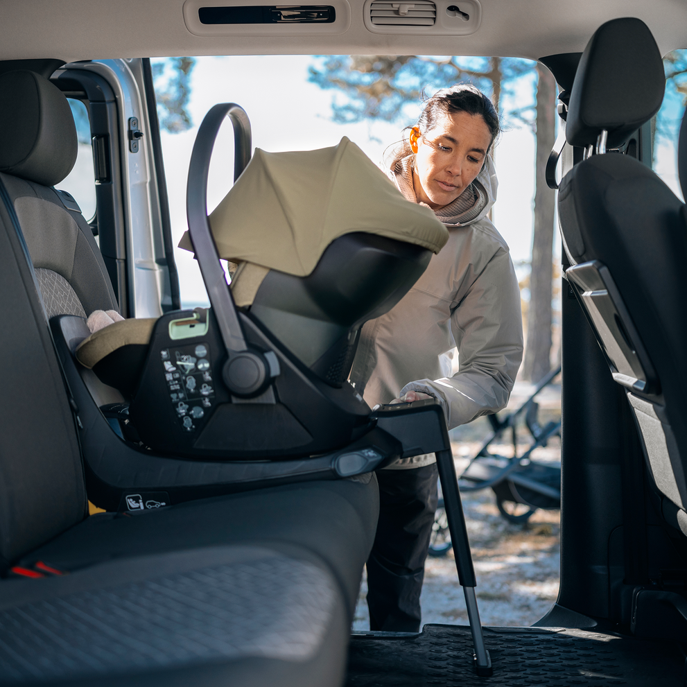 Adult attaching a Thule Maple Connect infant car seat to the Thule Alfi Connect ISOFIX base in the back seat of a vehicle.