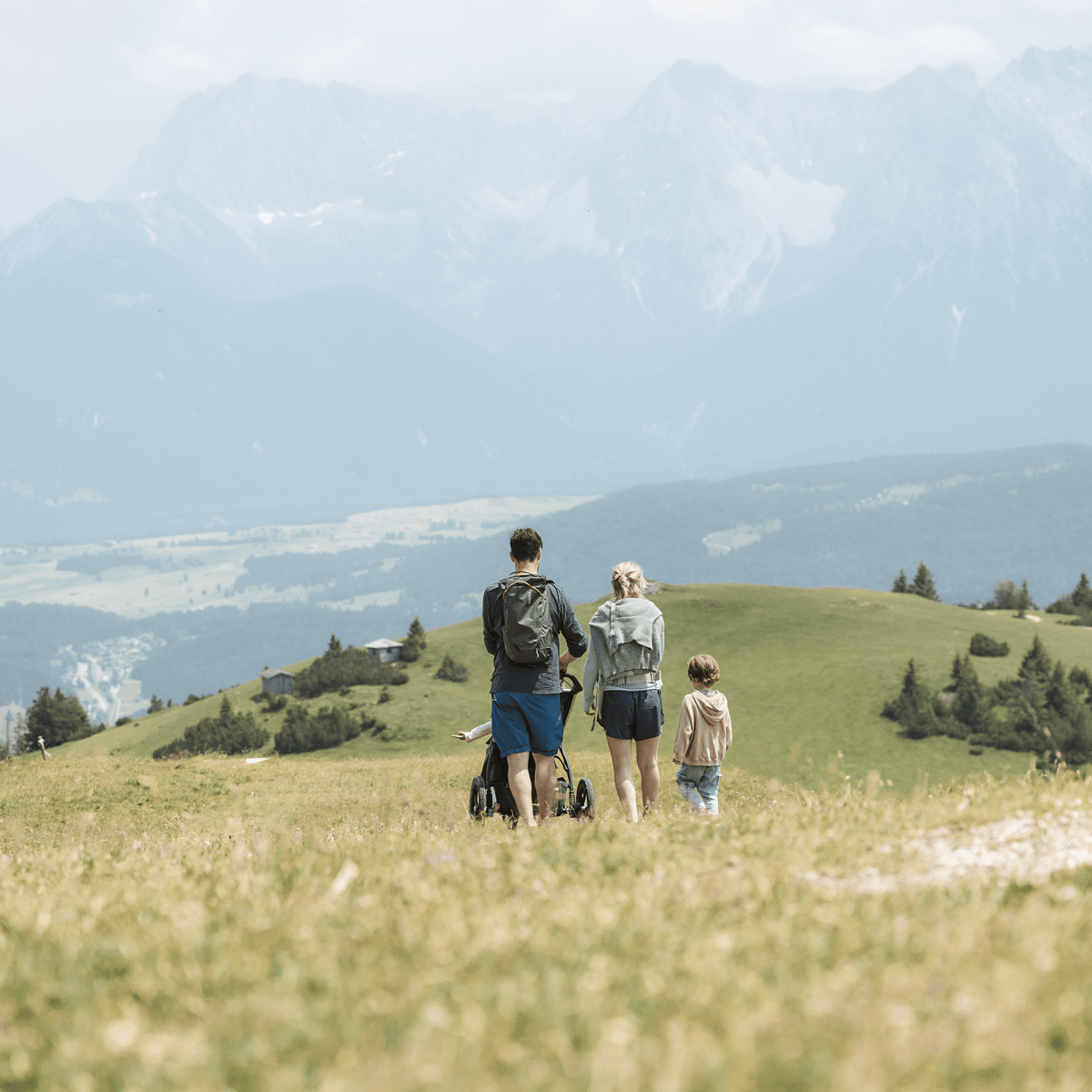 A family go for a stroll in the mountains carrying Thule Stir backpacks.