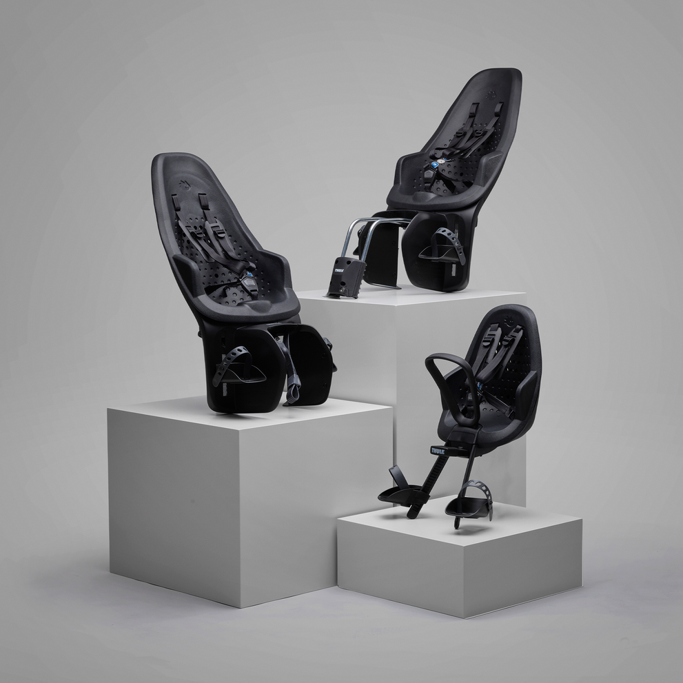 회색 배경에 세 개의 Thule Yepp 2 어린이 자전거 좌석이 받침대 위에 서 있다.