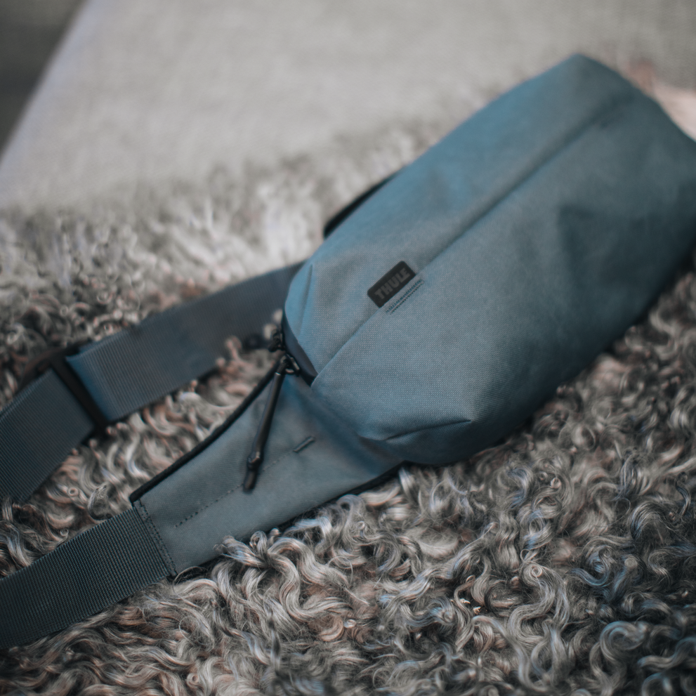 A close-up of the blue Thule Aion sling bag on a furry mat.
