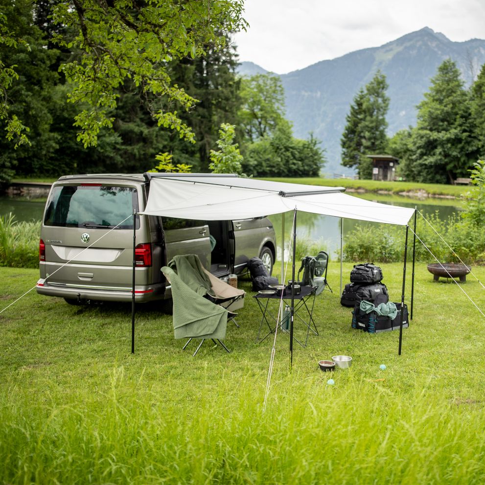 A van is parked in the mountains with a camp set up under the Thule Subsola awning panels.