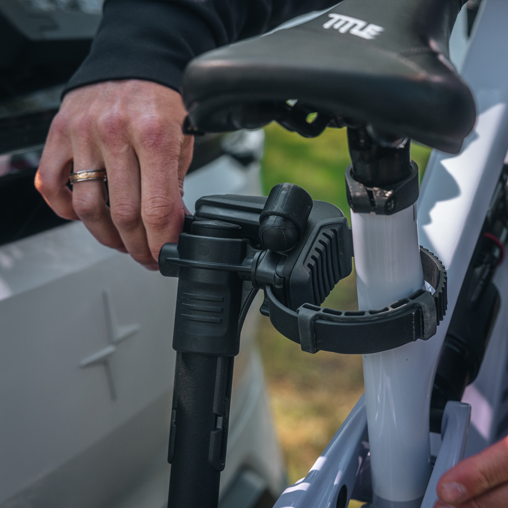 A man is making sure that the Thule VeloLite individual bike arms is strapped correctly to a bike.