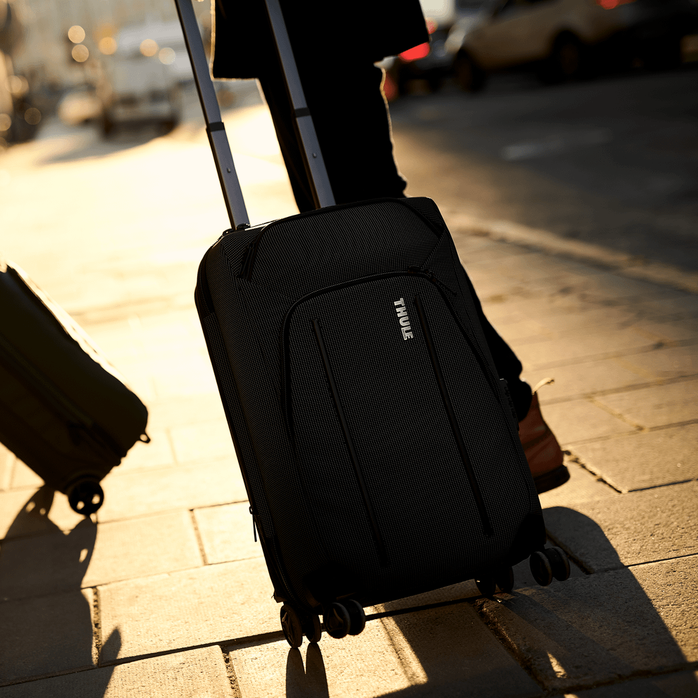 Two Thule Crossover 2 Expandable Carry-on suitcases stand on the sidewalk in the sunset.