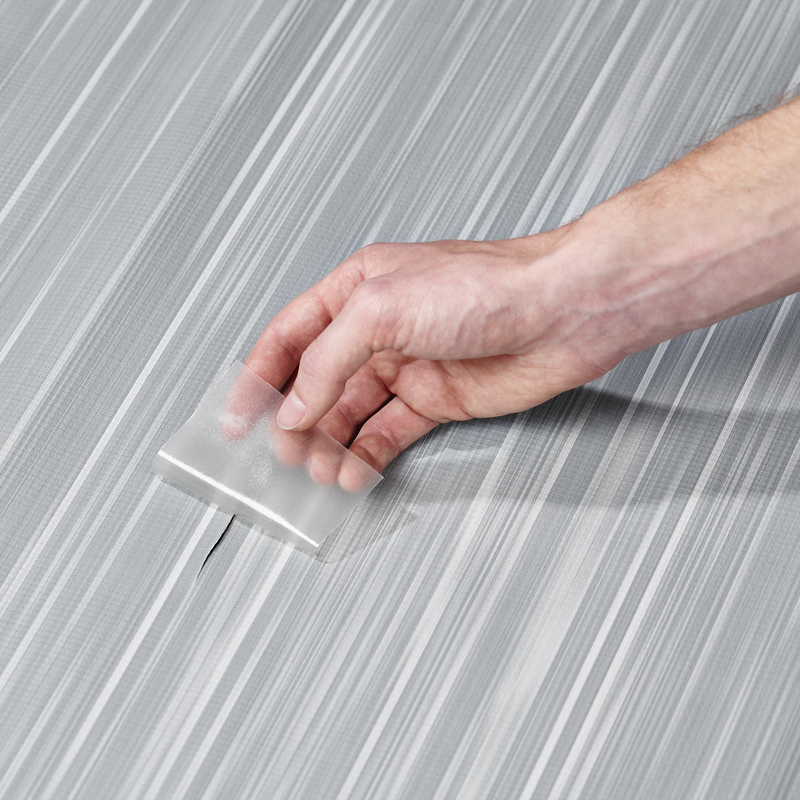 A person repairing an awning with a Thule Repair Patch.