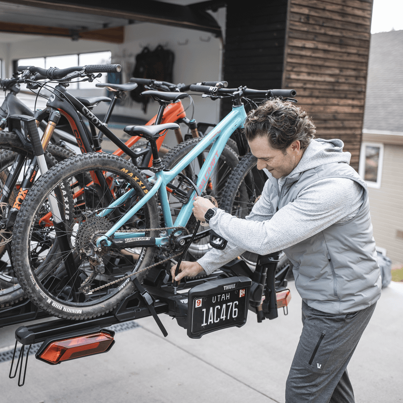 A man tilts the Thule Verse hitch bike rack with the 2 bike add-on.