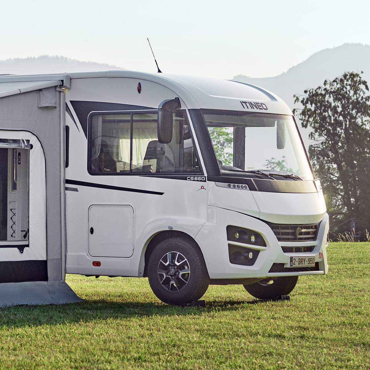 A motorhome is parked in the grass with a wheel on the Thule leveler.