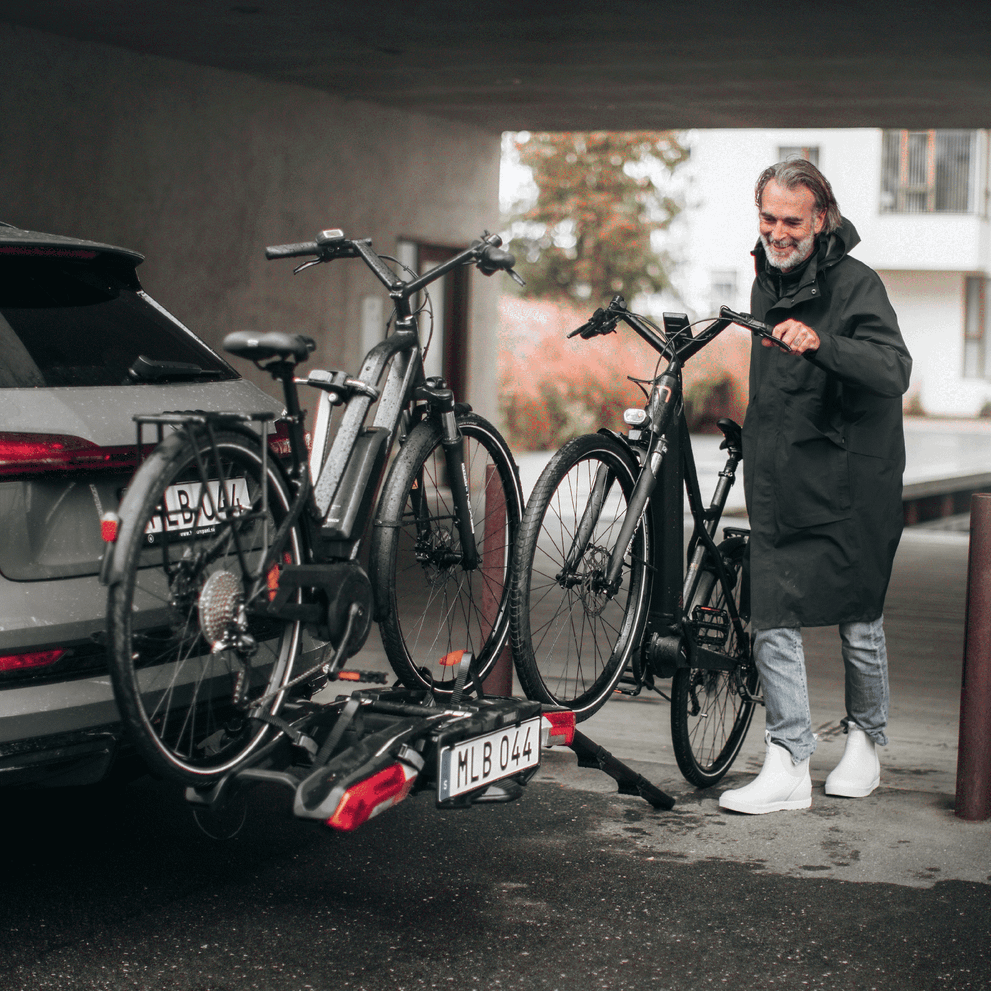 A man is loading a bike onto a Thule Epos bike carrier with a Thule Epos Foldable Loading Ramp