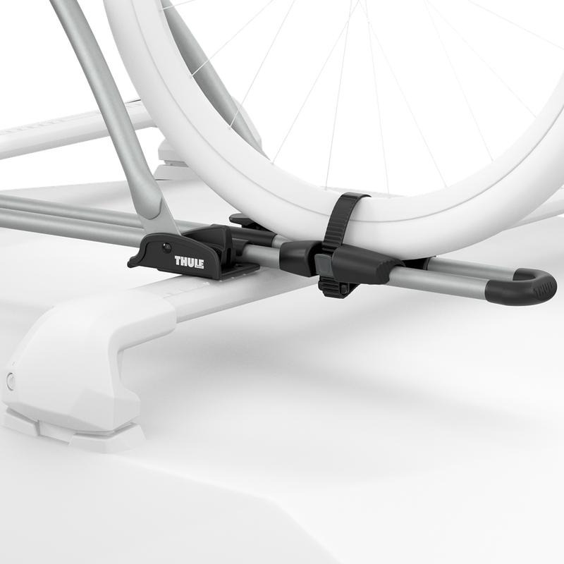 Close-up ghosted illustration showing the aluminum Thule FreeRide securing the bicycle wheels to the roof rack.