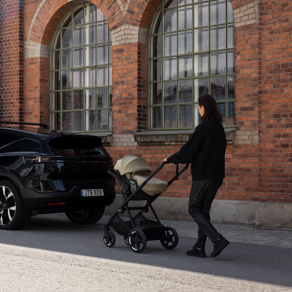 Adult pushing a Thule Charm stroller with an infant car seat attached using car seat adapters.