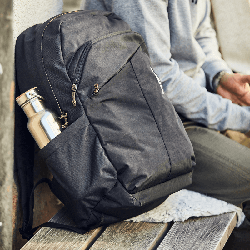 A man on a bike with a black helmet and a black Thule Indago backpack.