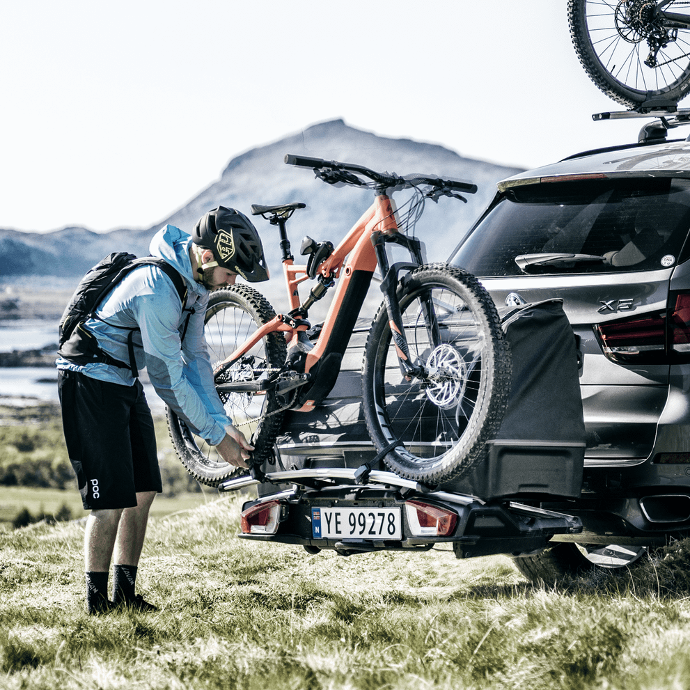 A man unloading his bike from a car with a Thule Backspace XT bike carrier.