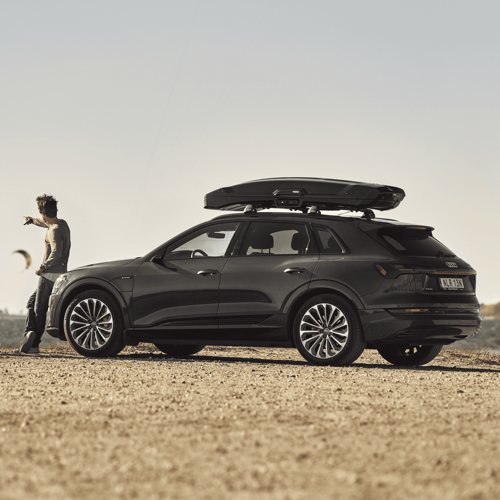 A man standing by a car with a Thule Vector cargo box.