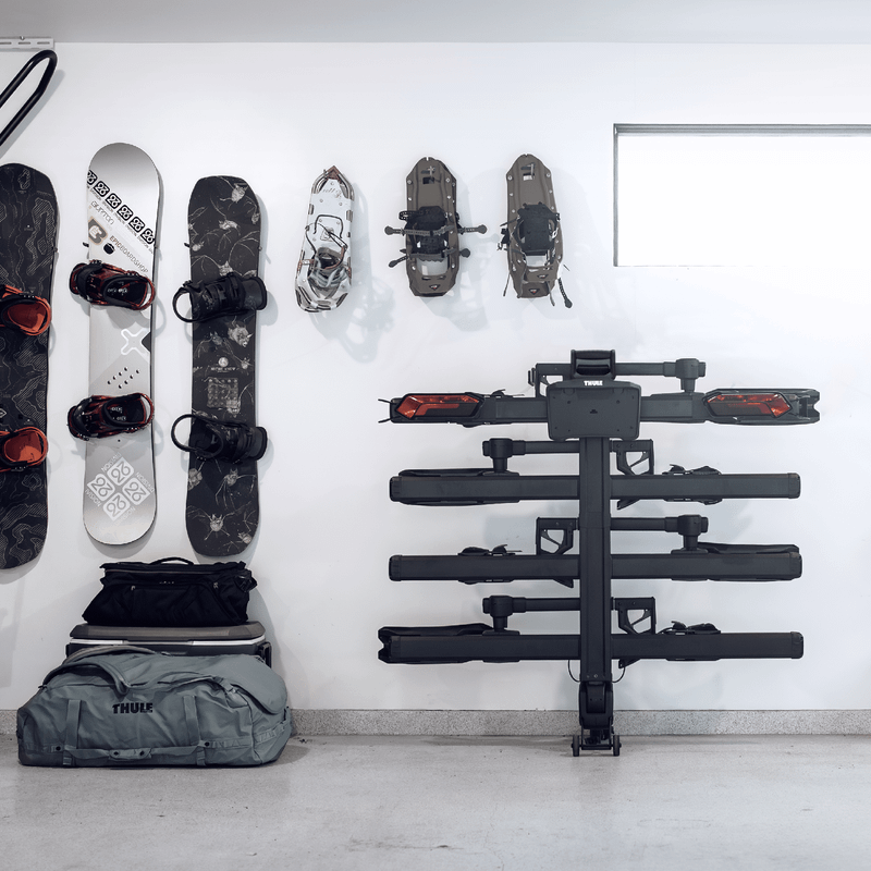 Thule Thule Verse hitch bike rack stands against a wall with outdoor gear.