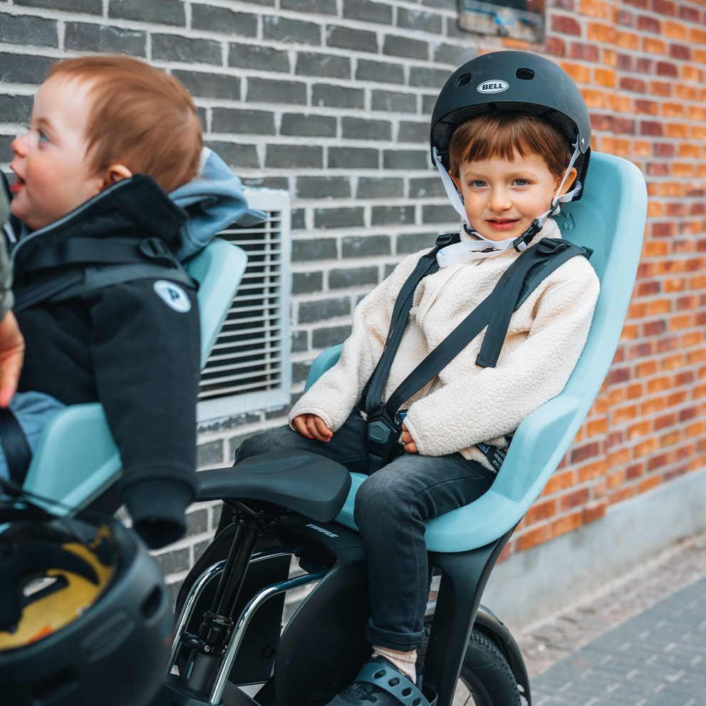 Close-up de un niño pequeño disfrutando del paseo en un asiento Thule Yepp 2, asegurado con un arnés.