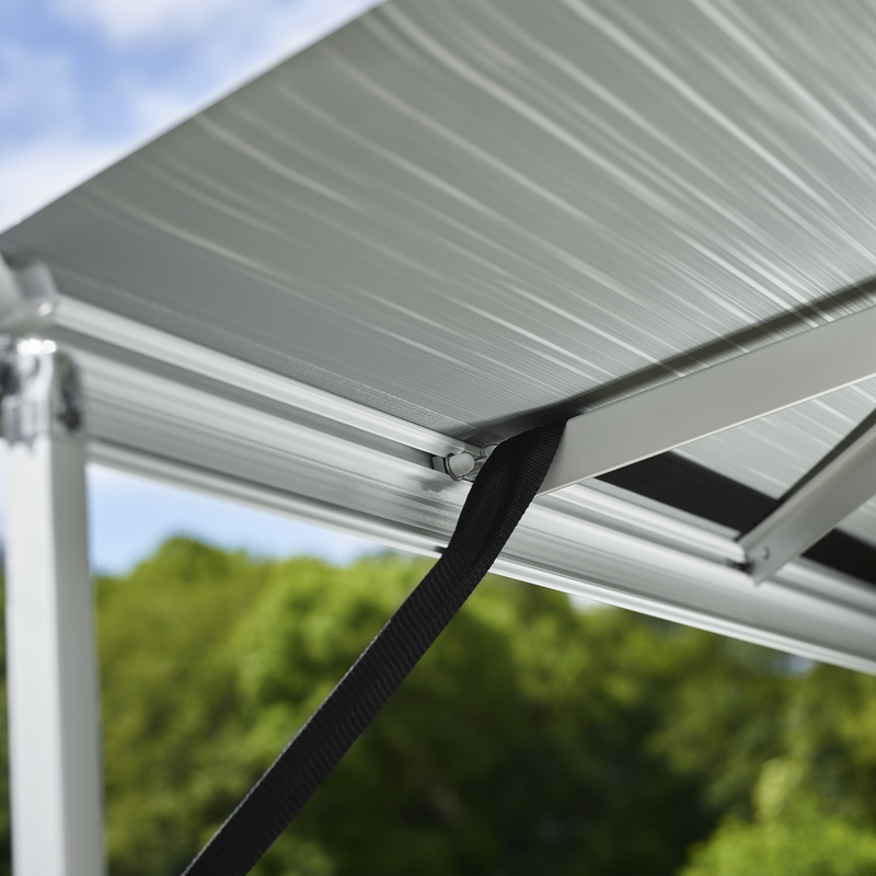 An awning with a Thule Hold Down Kit next to the backdrop of a blue sky.