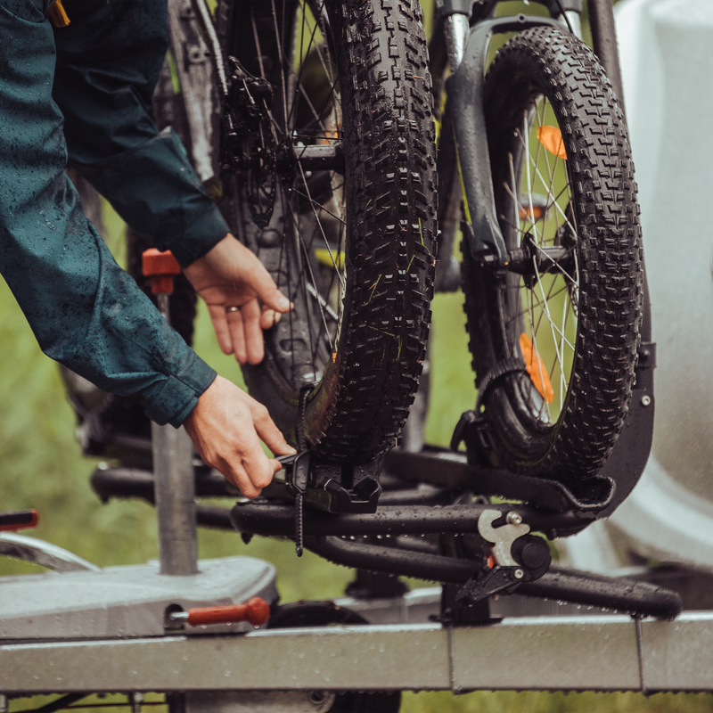 A person attaches a bike to a bike rack using a Thule Fatbike Rail Short Black.