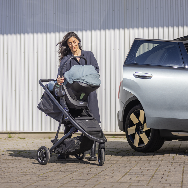 Woman attaching Thule Maple infant car seat to a Thule Spring stroller using the Thule Spring car seat adapter for Maxi-Cosi®.