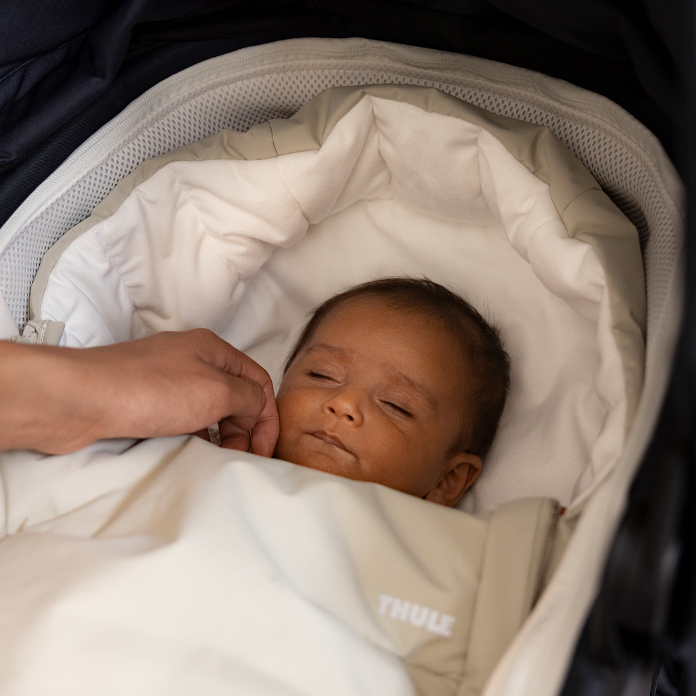 Baby resting comfortably in a stroller with the Thule Elements high-performance footmuff, keeping warm and cozy.