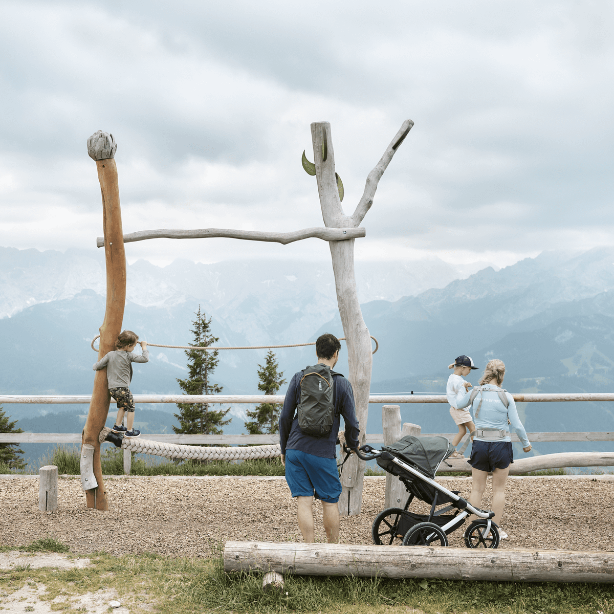 A family go for a stroll in the mountains carrying Thule Stir backpacks.