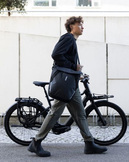 Thule Chasm courier with InLock 22L worn crossbody next to a bike