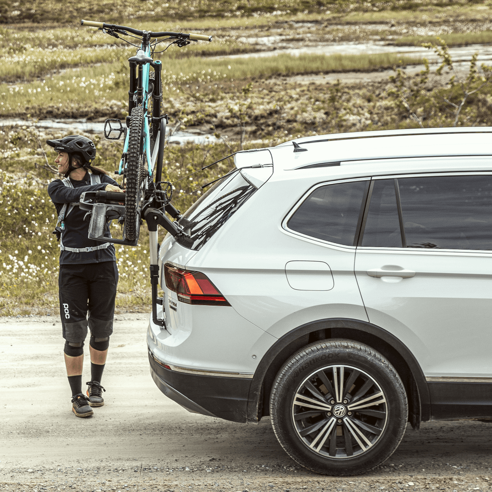 A cyclist loads her bike into the Thule OutWay 2bike Platform trunk bike rack.