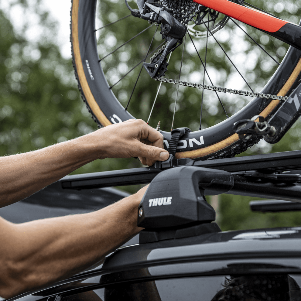 Closeup of a man who handles his bikes on a car with the bike carrier Thule TopRide