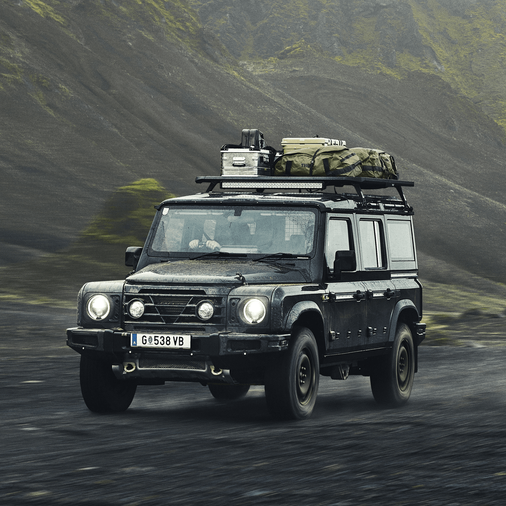A vehicle drives through the foggy countryside with a Thule Caprock roof platform.