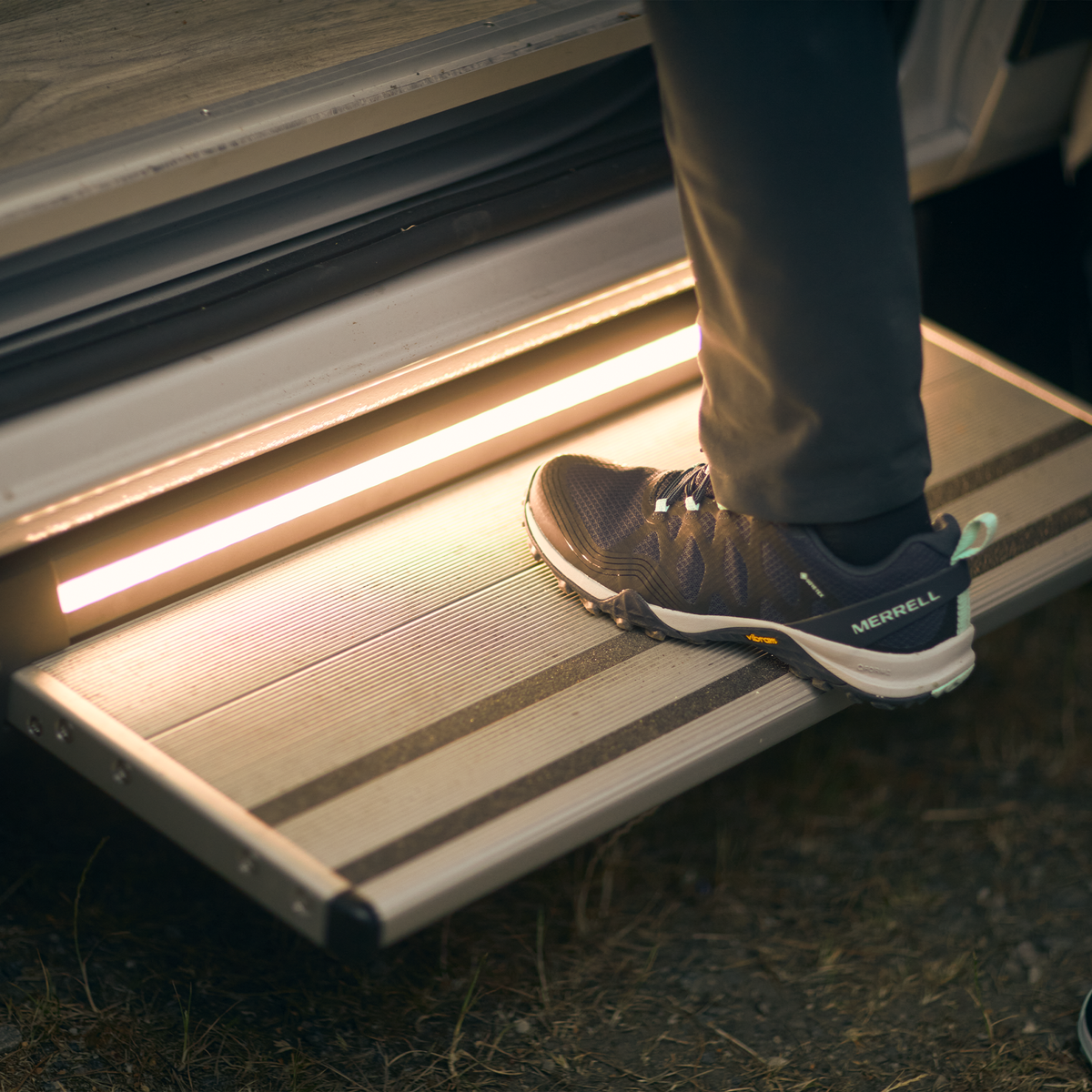A close-up of someone stepping on a caravan step with a Thule LED kit for Slide-Out Step Ducato.