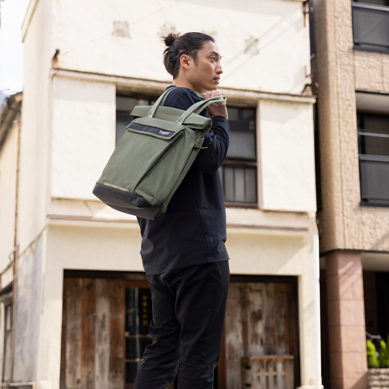 A man stands on a street corner with a Thule Paramount tote bag.