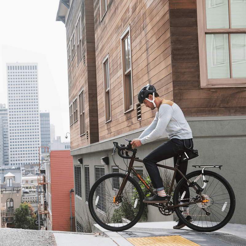 A man sits on his bike in a city, looking at his phone in a Thule Smartphone Bike Mount.