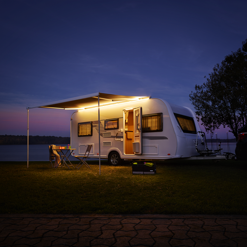 A caravan at night with lights and a Thule Tent LED Mounting Rail and RV lights.