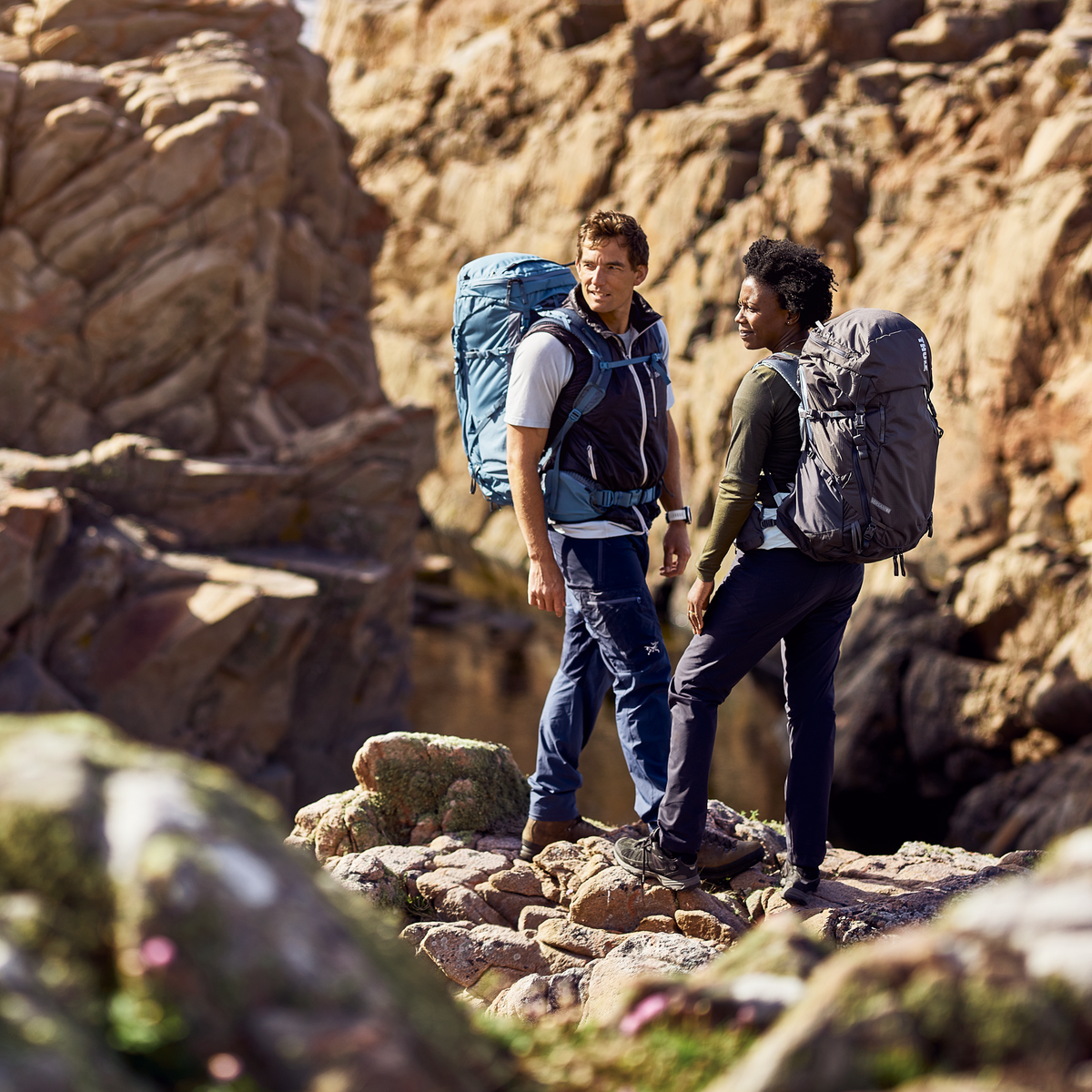 Two people stand in a rocky canyon carrying Thule Versant 50L backpacks.