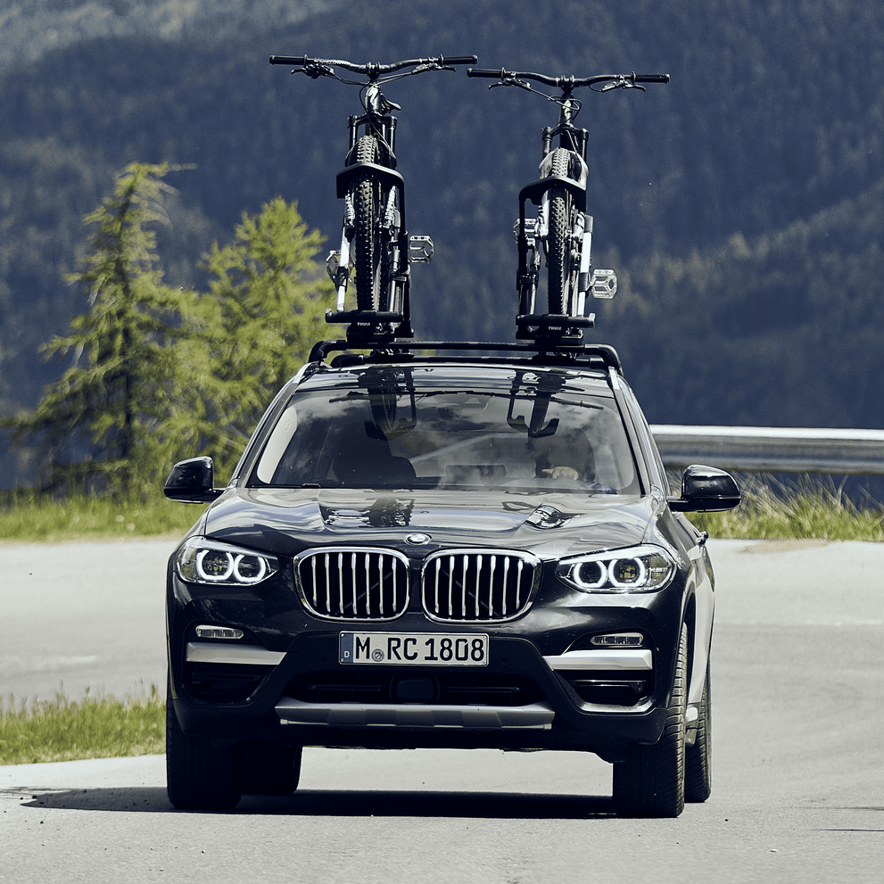 A car is approaching with bikes mounted on a Thule UpRide.