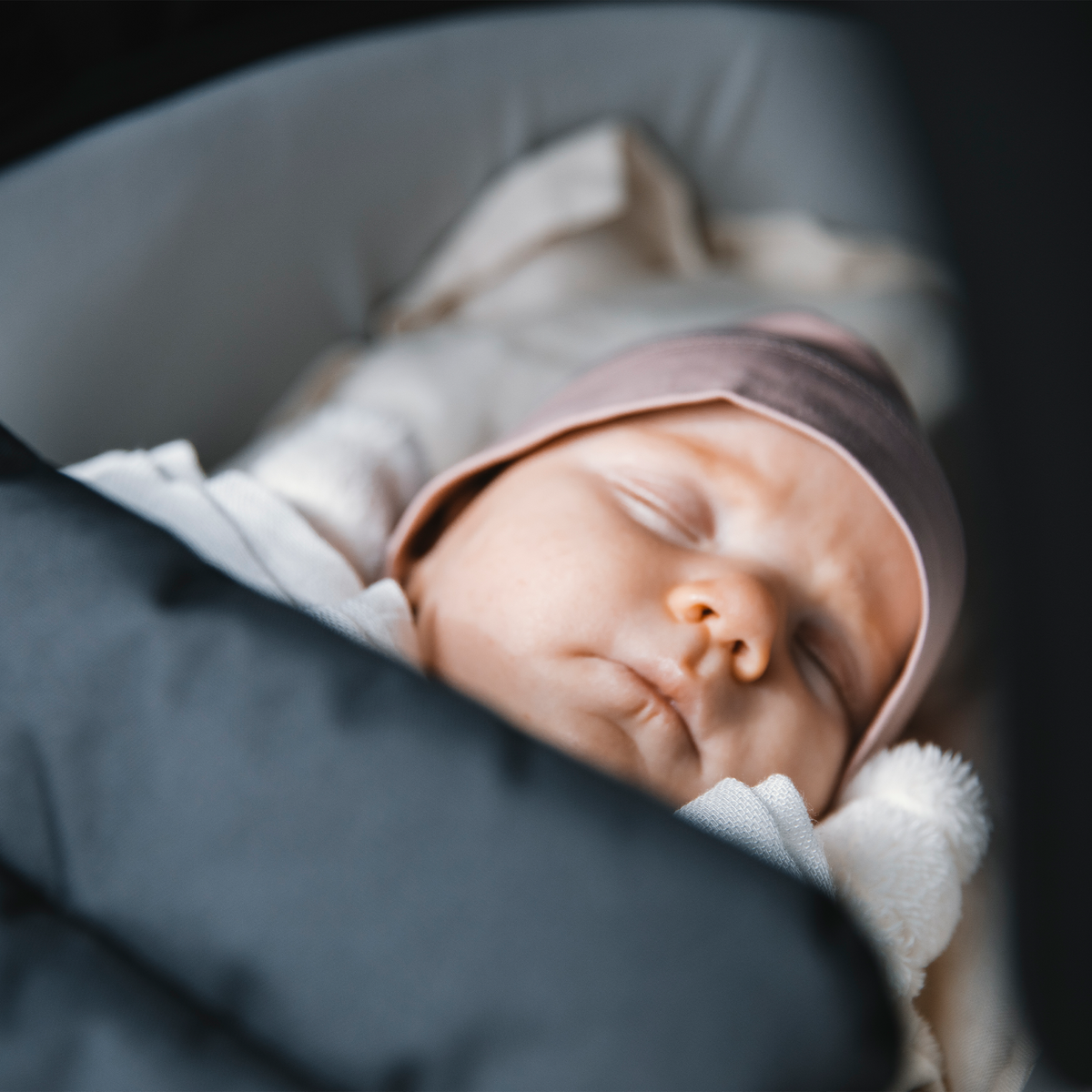 A close-up of a baby sleeping in a Thule Shine Bassinet.