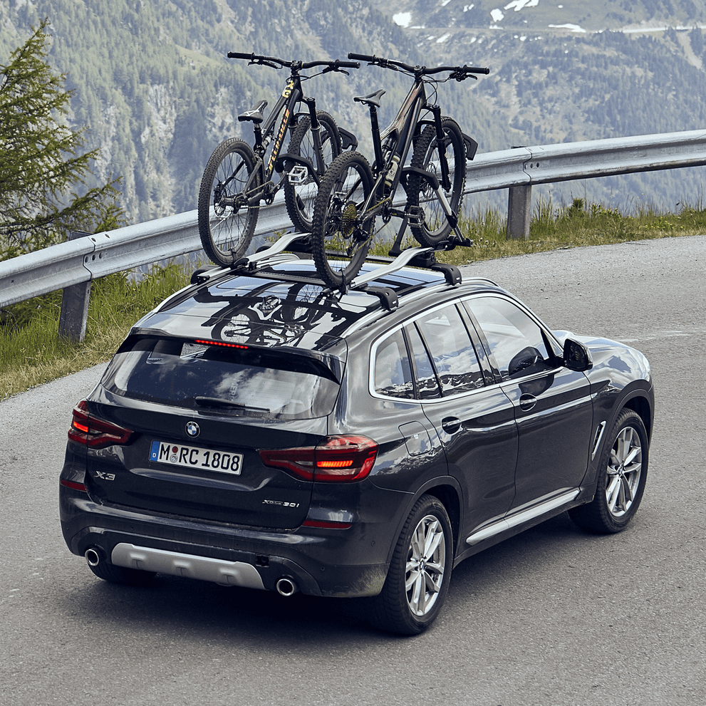 A car drives on a mountain road with bikes mounted on a Thule UpRide.