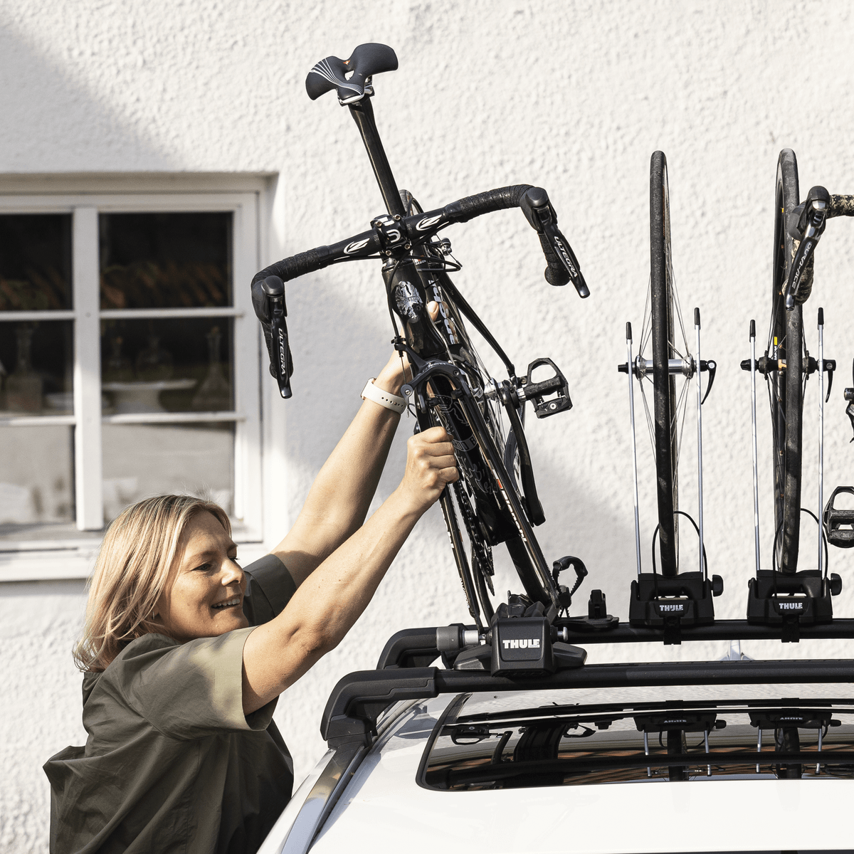 A couple is mounting their bikes on a car using Thule FastRide